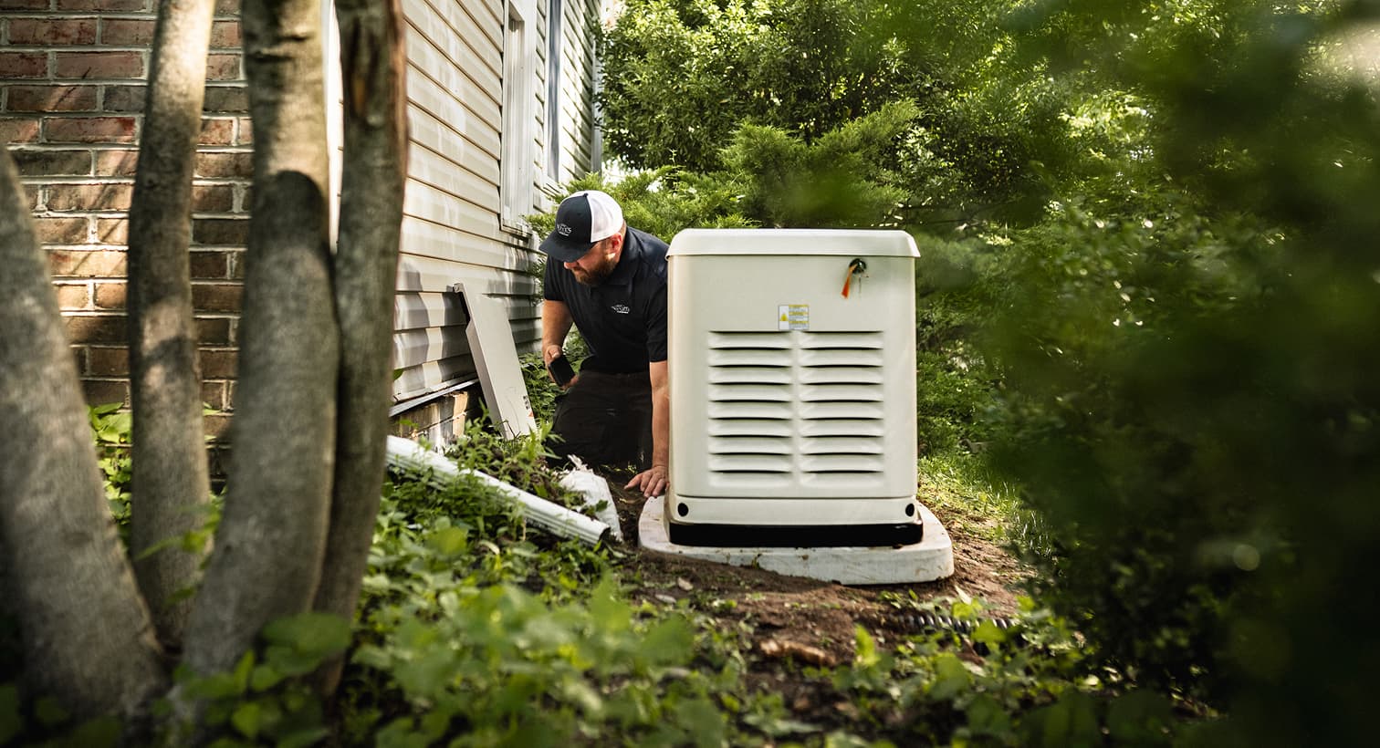 A professional Weeks technician inspects a large, beige whole-home standby generator installed on a concrete pad outside a residential house.