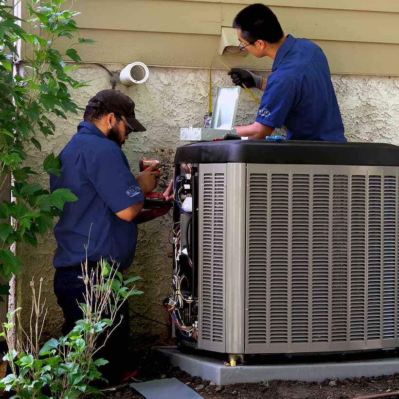 Two Weeks HVAC technicians installing a brand-new residential outdoor air conditioning condenser unit during a home AC replacement service.
